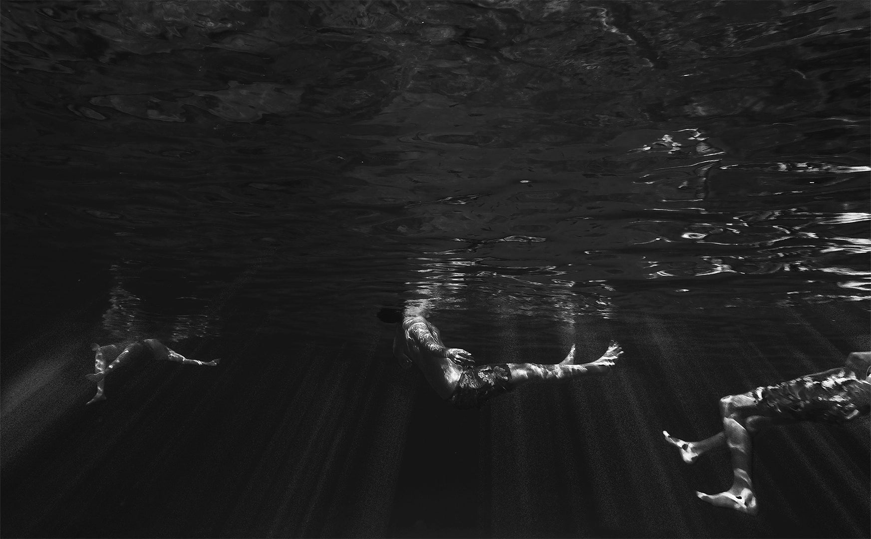 papadopavlos street photography. Underwater black and white photo. People in the sea from below. Human iceburgs