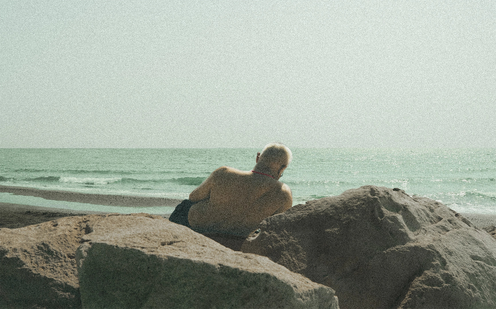 papadopavlos street photography. Old man chilling on the rocks, by the sea